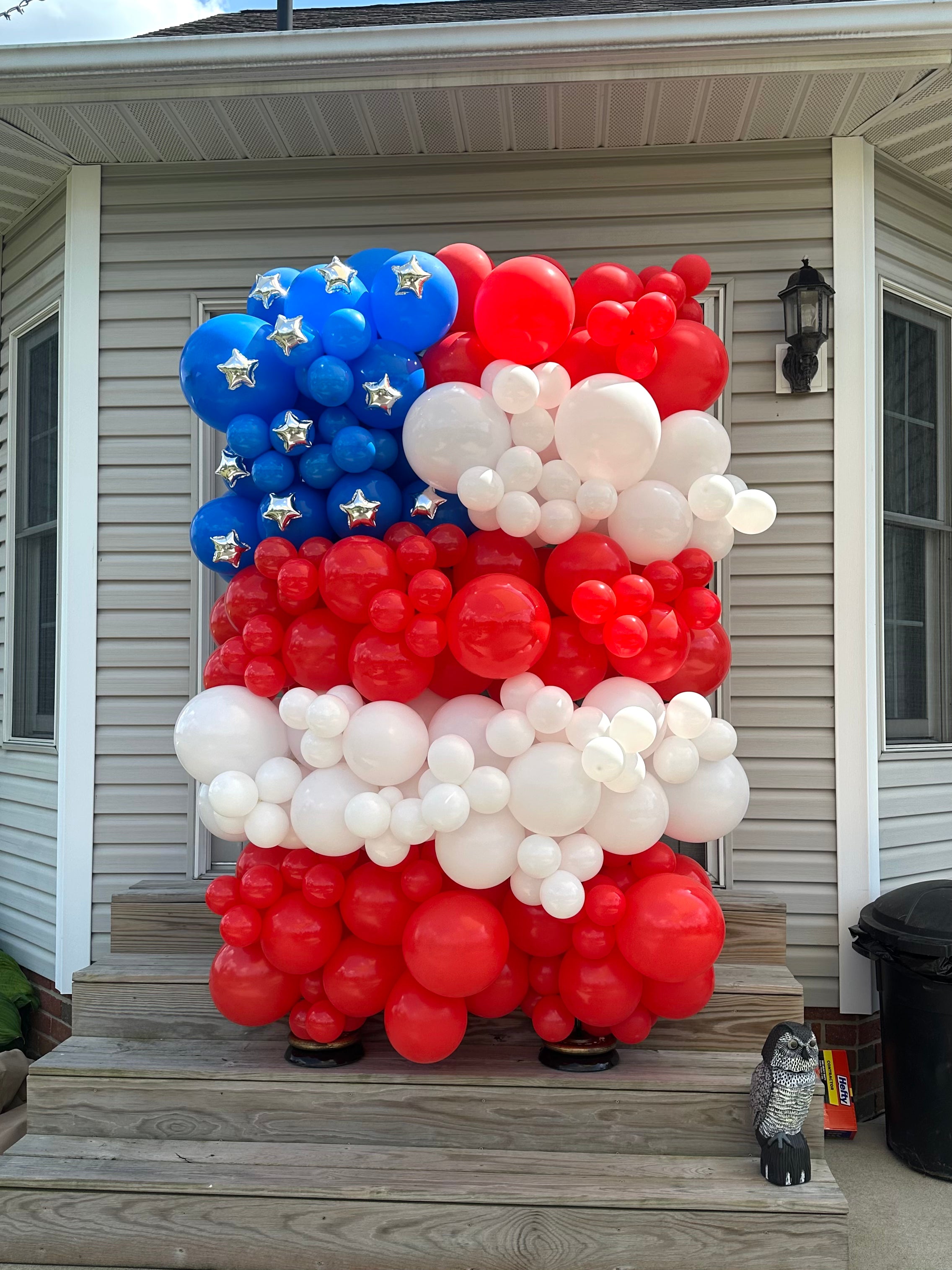 Balloon structure in the shape of an American flag with mini silver star balloons.